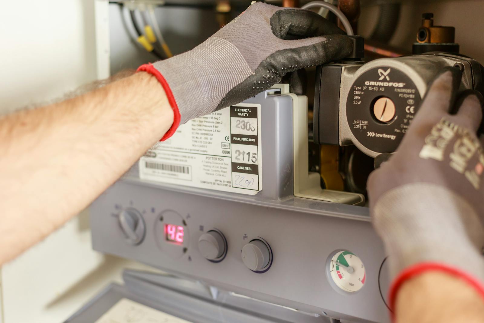 Gloved hands repairing water heating equipment