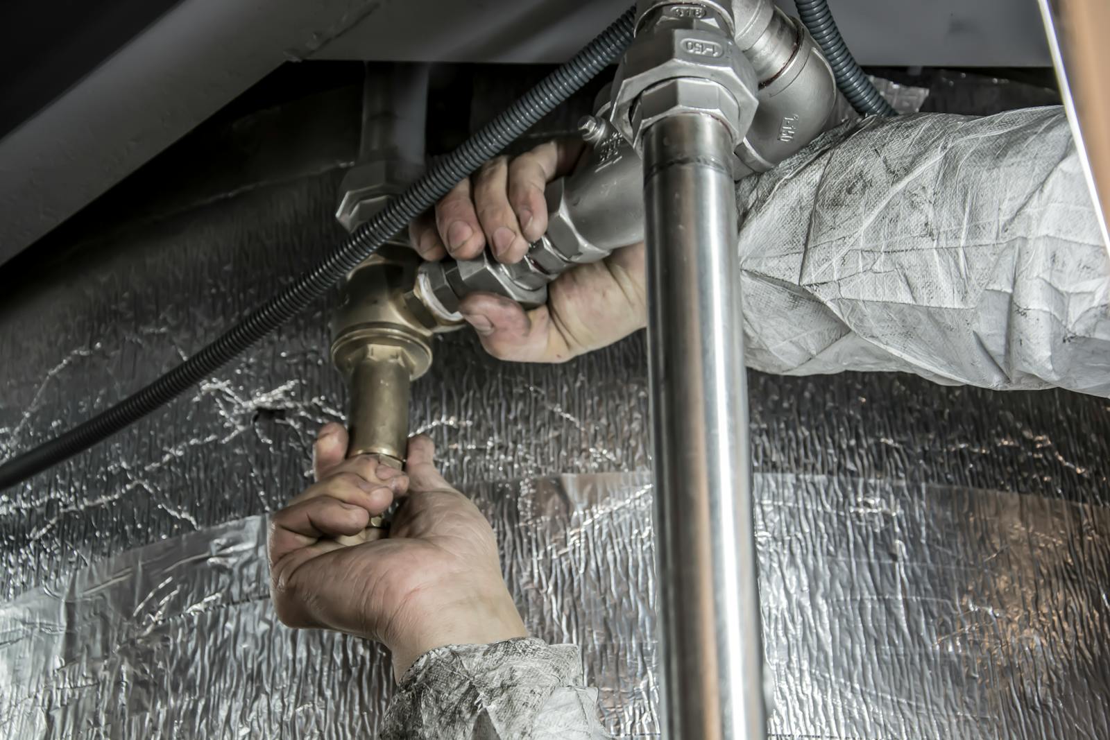 Plumber tightening metal pipe fittings